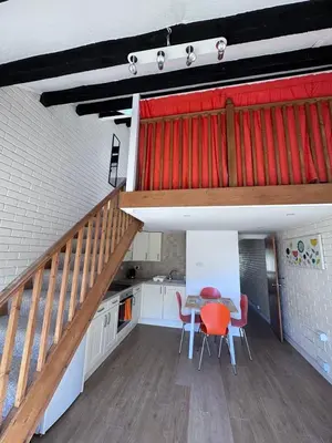 a kitchen with a table and chairs and a staircase at Surf 'n' Sands in Porthtowan Beachfront Apartment in Porthtowan