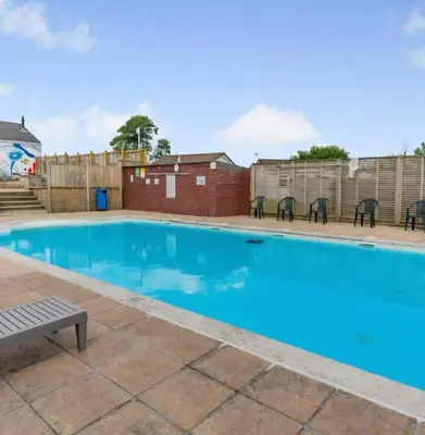 a swimming pool with chairs and a bench at Rural Retreat Chy Kensa a Hot Tub Haven in Grampound