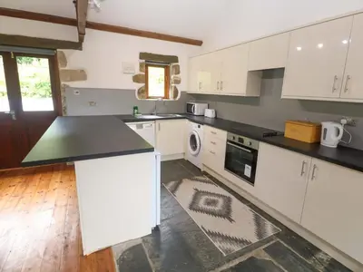 a kitchen with white cabinets and a black counter top at The Shippen in Penzance