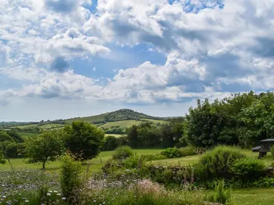 a view of a field with a mountain in the distance at The Old Workshop - Uk49871 in Lanivet