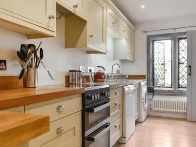 a kitchen with white cabinets and a stove top oven at Rivendell Cottage in Liskeard