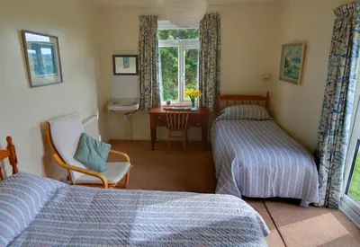a bedroom with two beds and a desk and a window at Wesdale Holiday Home in Polzeath