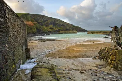 a beach with a stone wall and the ocean at Wesdale Holiday Home in Polzeath