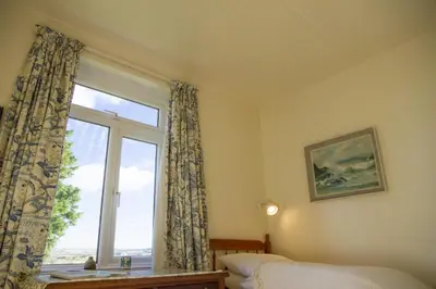 a bedroom with a window with a view of the ocean at Wesdale Holiday Home in Polzeath