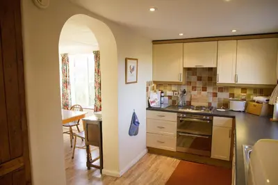 a kitchen with white cabinets and a dining room at Wesdale Holiday Home in Polzeath