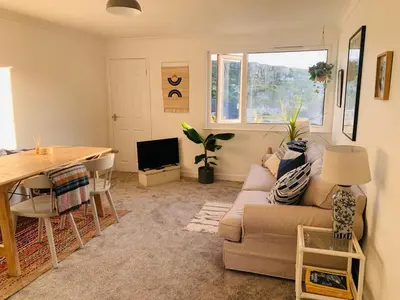 a living room with a couch and a table at Lovely two bed flat with a sea view next to beach in Porthtowan