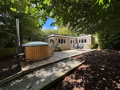 a small cabin with a deck in a yard at Cornish wooden cabin & wood fired hot tub in Gwennap
