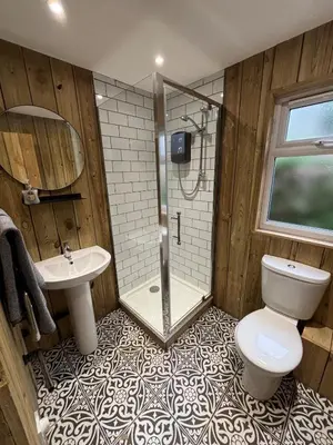 a bathroom with a shower and a toilet and a sink at Cornish wooden cabin & wood fired hot tub in Gwennap