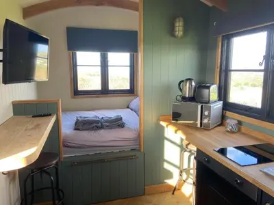 a small bedroom with a bed in a tiny house at Shepherds Hut in Mawgan Porth