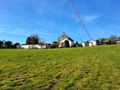 a green field with a house in the background at Bell Tent 1 in St Austell