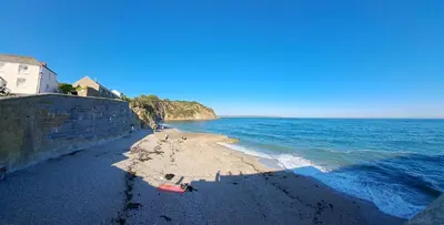 a beach with a retaining wall and the ocean at Bell Tent 1 in St Austell