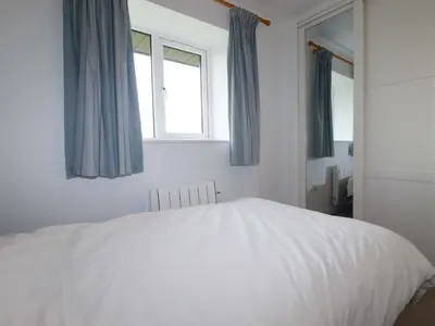 a white bed in a bedroom with two windows at Folly View in Redruth