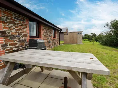 a wooden picnic table in front of a brick building at Folly View in Redruth