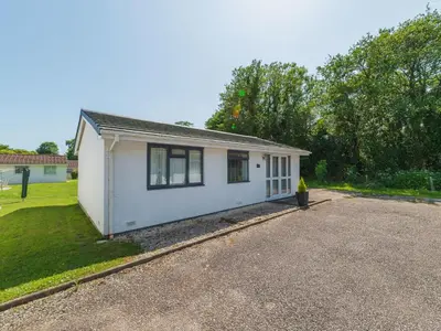 a small white house on a gravel road at Chalet Rosecraddoc Lodges by Interhome in Liskeard