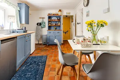 a kitchen with blue cabinets and a table and chairs at Captains Ground in Altarnun