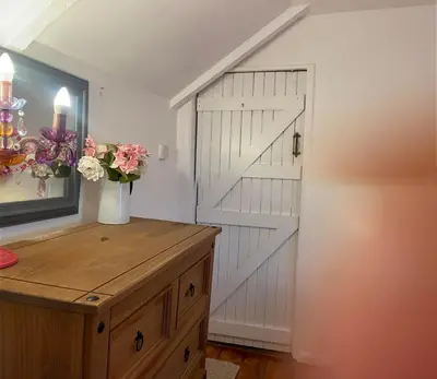 a barn door in a room with a vase of flowers at Captains Ground in Altarnun