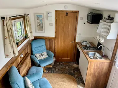 a small kitchen with two chairs and a sink in a trailer at Morthana Shepherd Hut in Scorrier