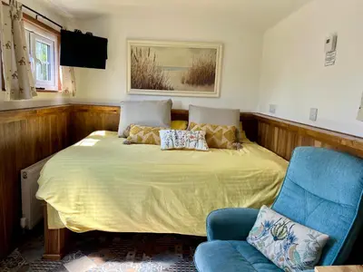 a bedroom with a bed and a blue chair at Morthana Shepherd Hut in Scorrier