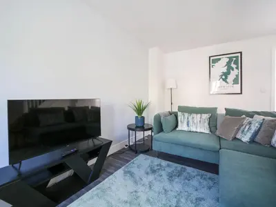 a living room with a green couch and a flat screen tv at Canyke Fields in Bodmin
