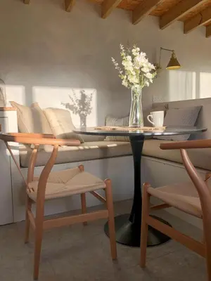 a dining room with a table with a vase of flowers on it at SeaNest, Aggie Home by the sea in St. Agnes