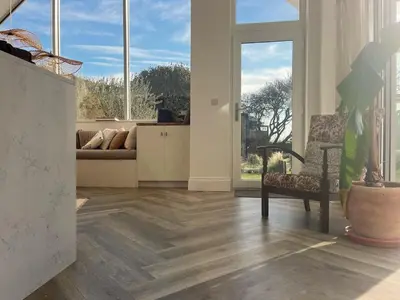 a living room with wooden floors and large windows at SeaNest, Aggie Home by the sea in St. Agnes