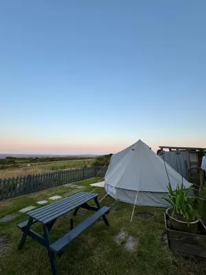 a tent and a picnic table in the grass at Emilies Bell Tent in St Ives