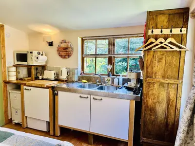 a kitchen with white cabinets and a sink and a window at Harvey's Lodge in Helston