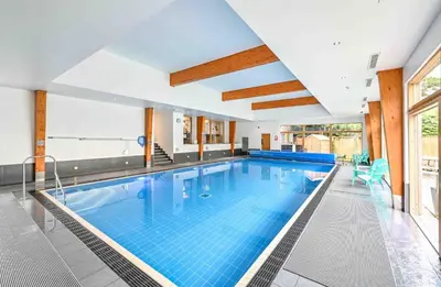 a large swimming pool with blue tiles in a building at House 19 in Looe