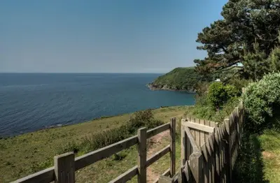 a wooden fence next to a body of water at House 29 in Looe