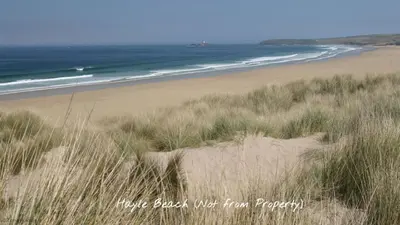 a sandy beach with grass and the ocean at D21 Treville, Riviere Towans in Hayle