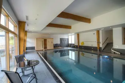 a large swimming pool with a table and chairs at House 30 in Looe