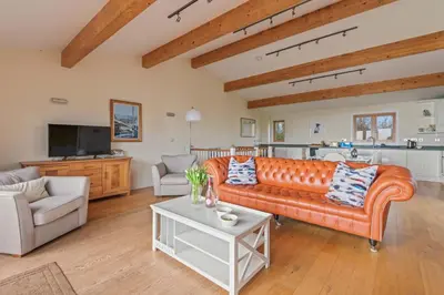 a living room with an orange couch and a table at House 36 in Looe