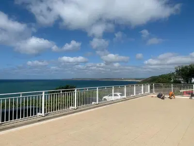 a person laying on a balcony looking at the ocean at Stunning 2 bedroom modern apartment! Amazing views! in Carbis Bay