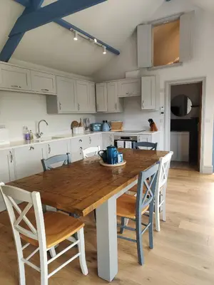 a kitchen with a wooden table and white cabinets at Ocean Heart Studio- Luxury, Rural Retreat in Wendron