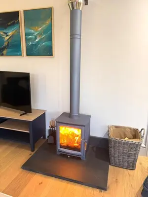 a wood stove in a living room with a tv at Ocean Heart Studio- Luxury, Rural Retreat in Wendron