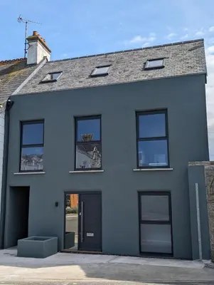 a white house with a black door and windows at Shorebreak Apartment 2 in Newquay