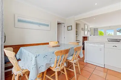 a kitchen with a blue table and chairs at Chough at Highcliffe in Polzeath