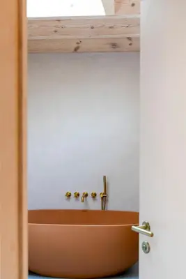 a wooden tub in a bathroom with a white wall at The Architects Treehouse in Mount Hawke