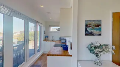 a kitchen with white walls and a large window at D08 Dawn O Day, Riviere Towans in Hayle