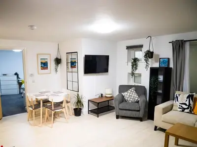 a living room with a couch and a table and chairs at Modern surf pad, steps from Towan beach in Newquay