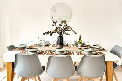 a dining table with chairs and a vase with flowers at Cornish house, close to beaches - Ashfield Villas in Falmouth