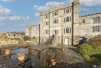 a large stone building with a pond in front of it at Acton Castle in Praa Sands