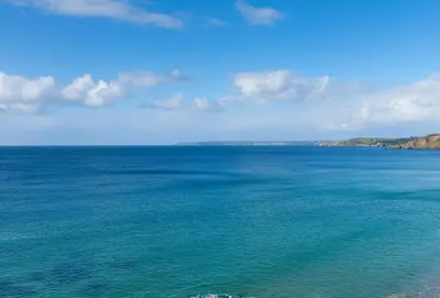 a large body of water with a blue sky and clouds at Acton Castle in Praa Sands