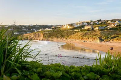 a beach with a group of people in the water at The Treyarnon Suite in St Merryn