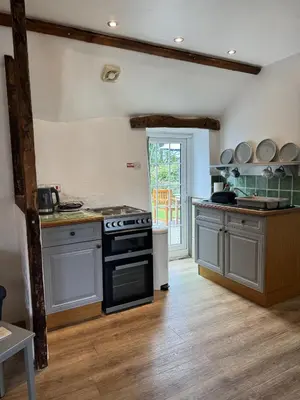a kitchen with a stove top oven in a room at Titmouse at Trenale Court Cottages in Tintagel