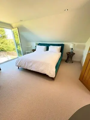 a bedroom with a bed with white sheets and a window at Porth Beach Lodge in Saint Columb Minor