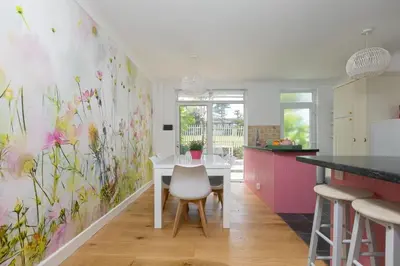 a kitchen with a white table and flowers on the wall at Pebble in Carbis Bay