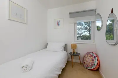 a bedroom with a bed and two windows at Pebble in Carbis Bay