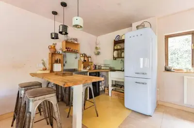 a kitchen with a wooden table and a refrigerator at The Birch House in Saint Columb Major