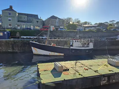 two boats are docked at a dock in the water at Bell Tent 2 in St Austell